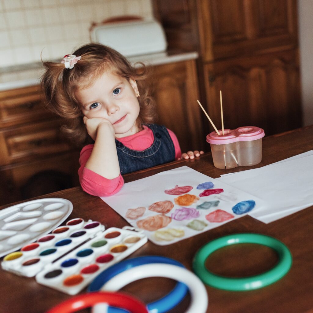 Cute little girl draws a circle of colored paints