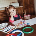 Cute little girl draws a circle of colored paints