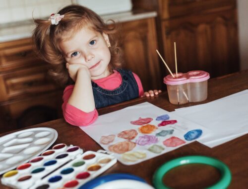 Cute little girl draws a circle of colored paints