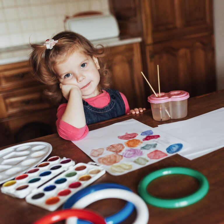 Cute little girl draws a circle of colored paints