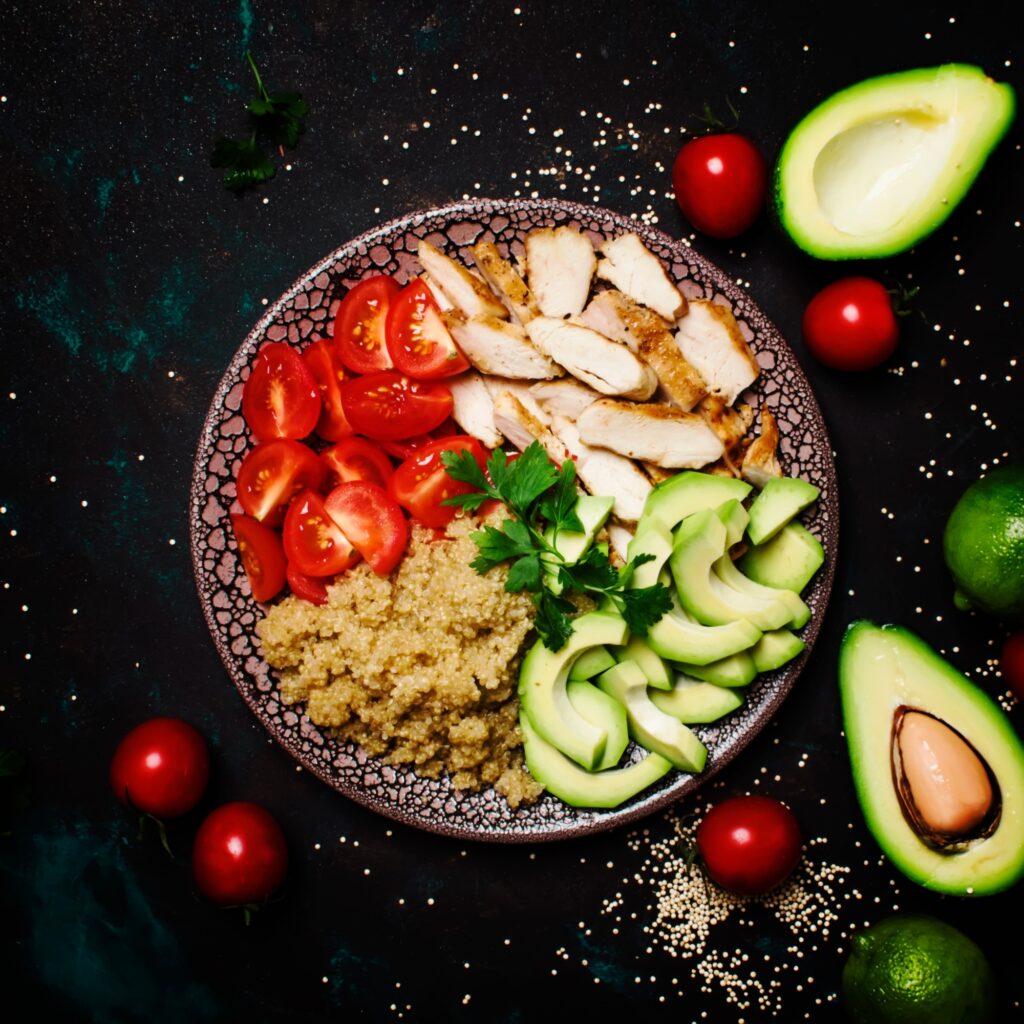 Healthy food, avocado, quinoa, chicken and tomatoes on plate, top view