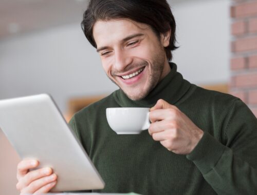 Young successful businessman checking emails while having morning coffee